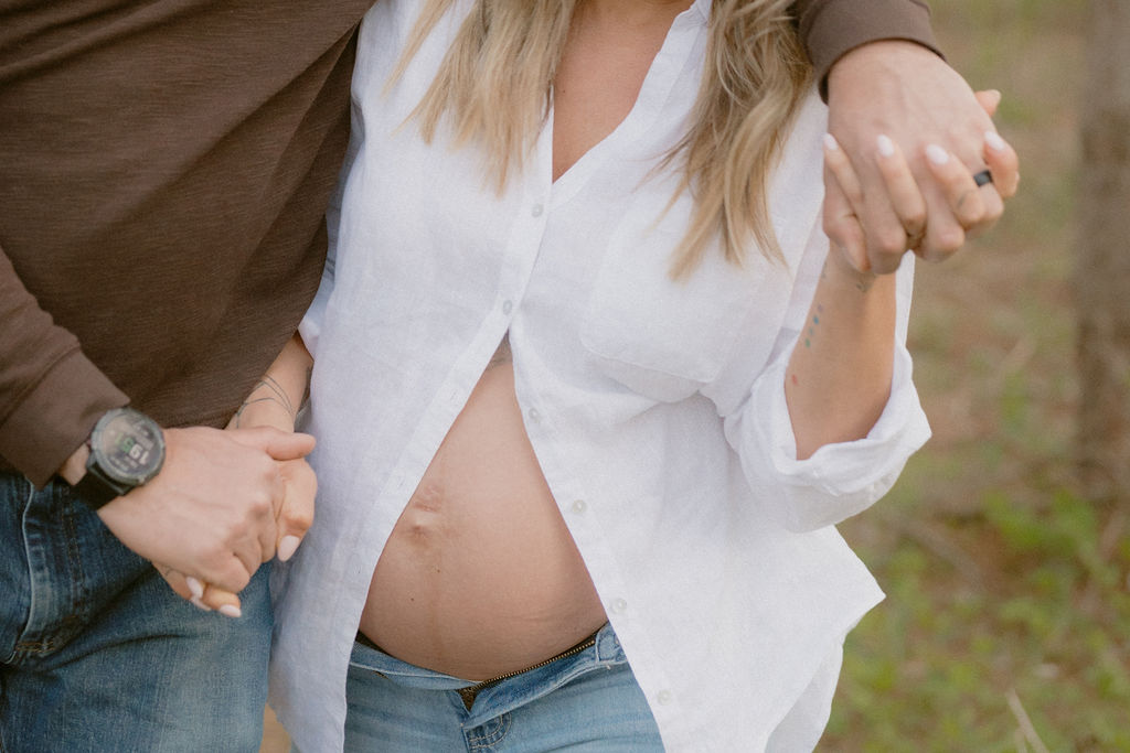 Close-up fine art film pregnancy portrait of a mother gently cradling her belly during sunset.